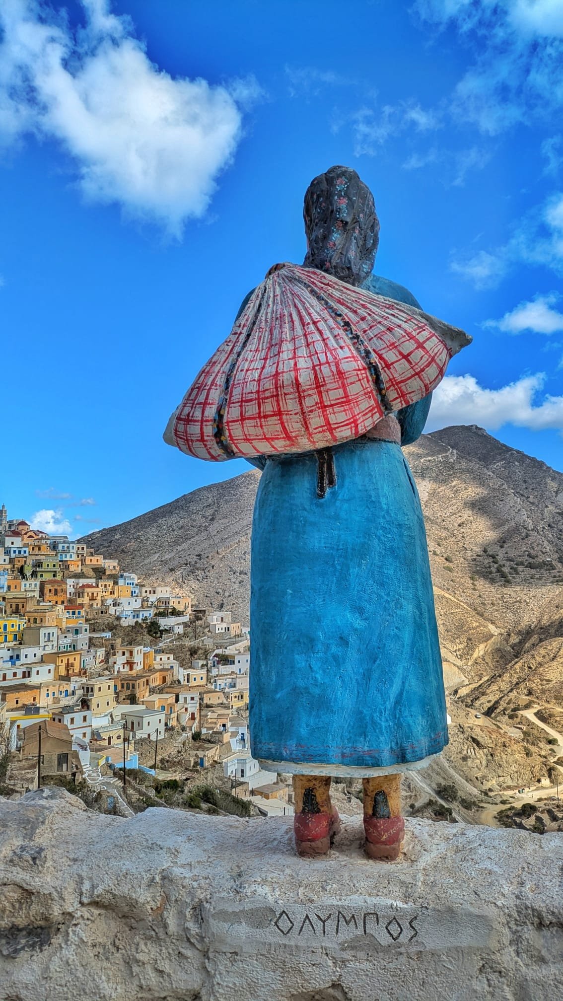 Statua in costume tradizionale karpatiaco con il villaggio di Olympos sullo sfondo