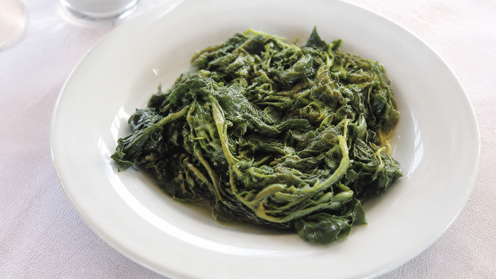 Tavola apparecchiata con piatti tipici e verdure in una taverna di Karpathos