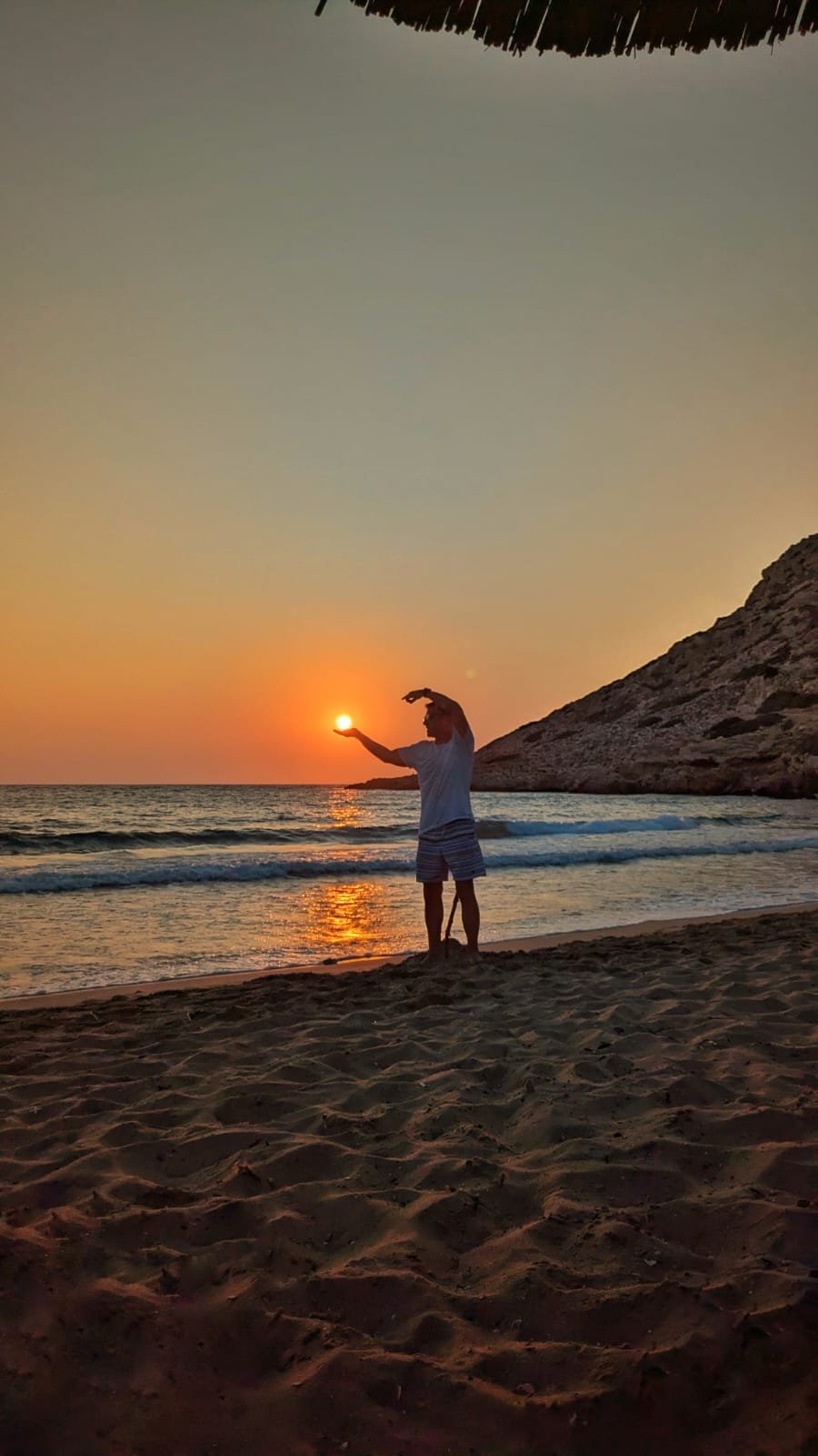 Silhouette di persone al tramonto con il sole tra le mani in riva al mare di Karpathos